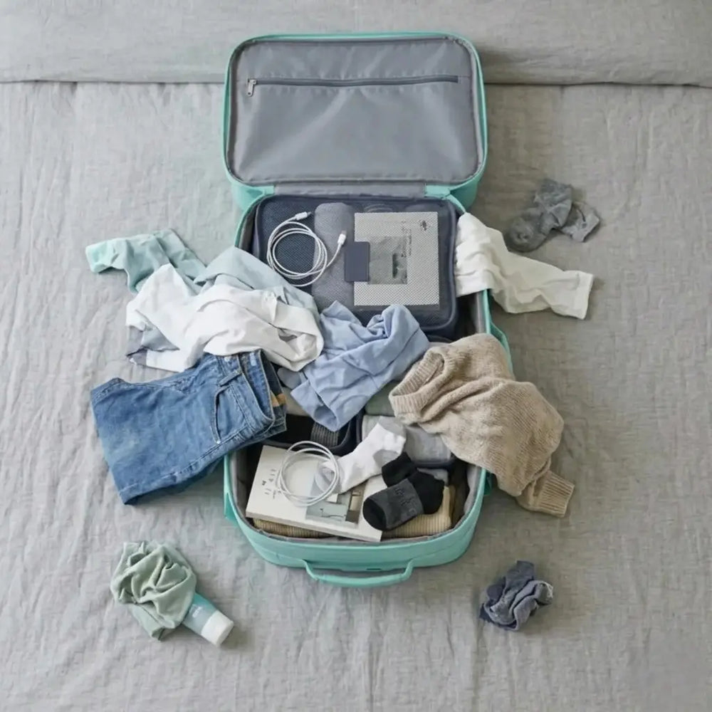 מזוודה עם בגדים וציוד מפוזרים ללא ארגון באמצעות ארגוניות אריזה